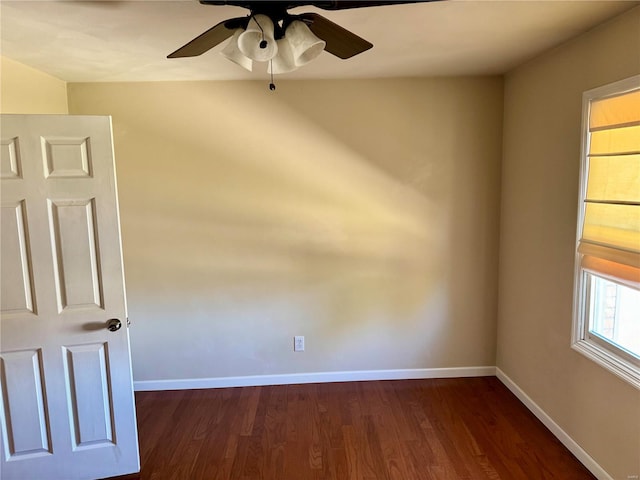 unfurnished room with baseboards, ceiling fan, and dark wood-style flooring