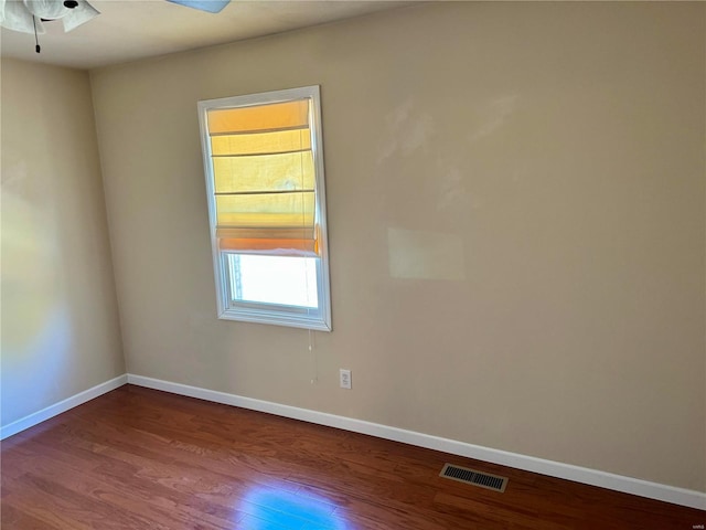 empty room featuring a ceiling fan, wood finished floors, visible vents, and baseboards