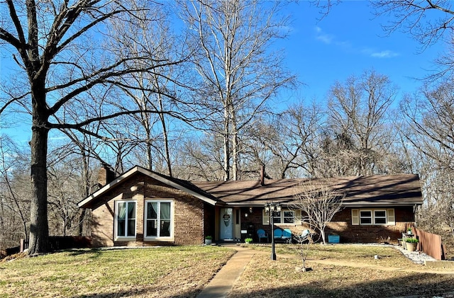 view of front of home with brick siding, a chimney, and a front lawn