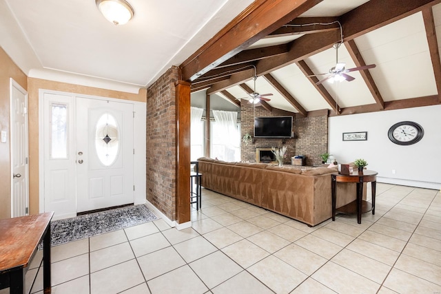 foyer with a ceiling fan, lofted ceiling with beams, brick wall, light tile patterned floors, and a brick fireplace