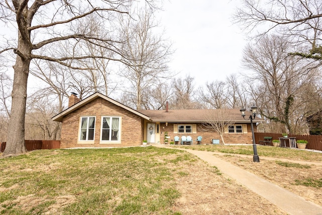 view of front of home with a front lawn, fence, brick siding, and a chimney