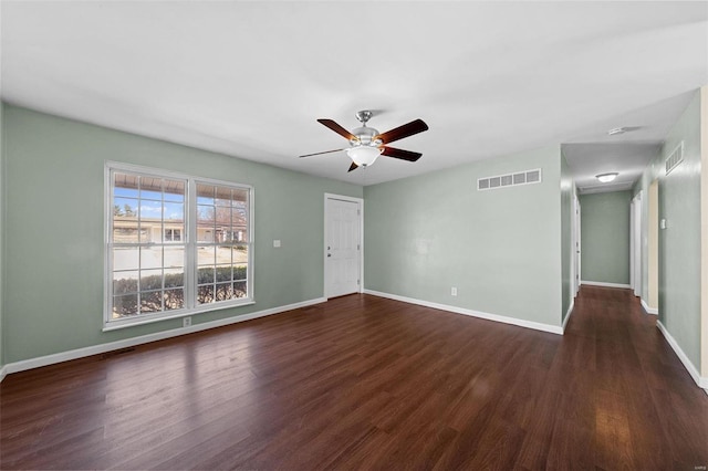 spare room featuring dark wood finished floors, baseboards, visible vents, and a ceiling fan