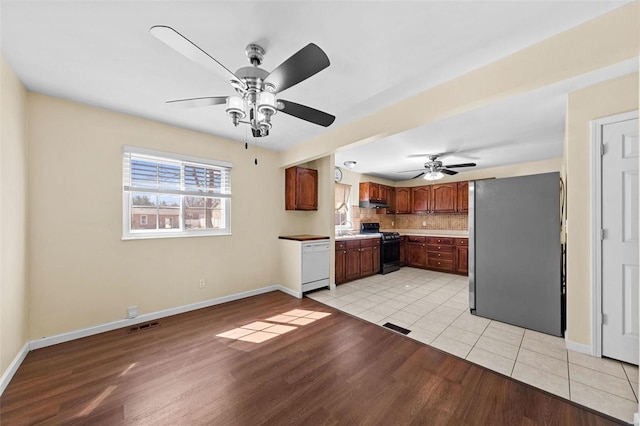 kitchen with gas stove, light wood-style flooring, freestanding refrigerator, dishwasher, and tasteful backsplash