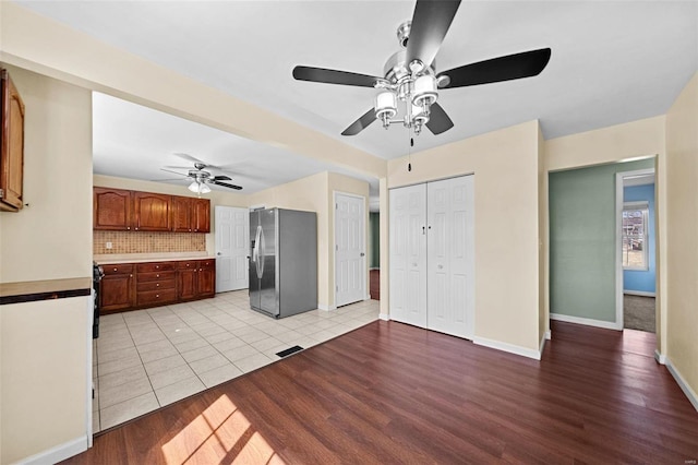 kitchen featuring visible vents, stainless steel refrigerator with ice dispenser, backsplash, light wood-style floors, and baseboards