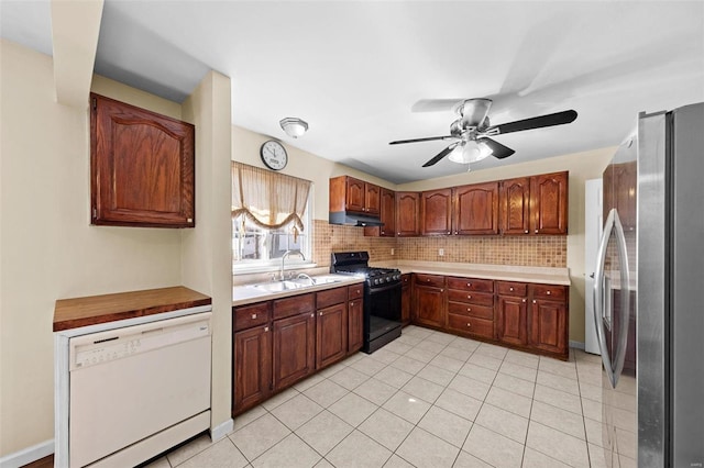 kitchen featuring under cabinet range hood, backsplash, freestanding refrigerator, black gas stove, and dishwasher