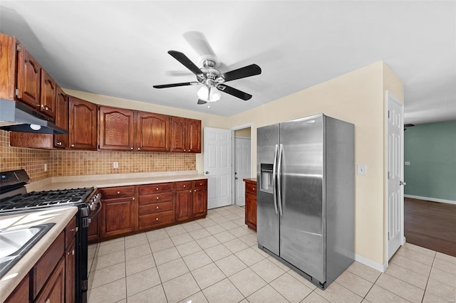 kitchen featuring black range with gas cooktop, under cabinet range hood, tasteful backsplash, and stainless steel refrigerator with ice dispenser