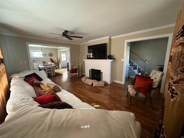 living room with stairs, a fireplace, wood finished floors, and crown molding