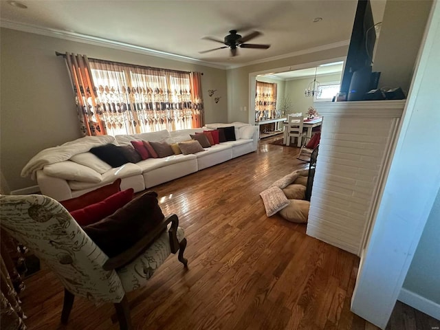 living area with a ceiling fan, ornamental molding, and wood finished floors