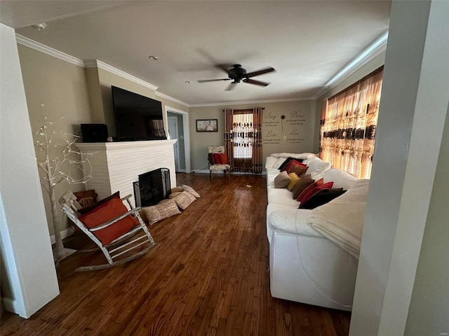 living area featuring ceiling fan, ornamental molding, a brick fireplace, and wood finished floors