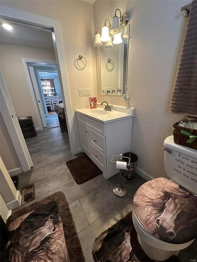 bathroom featuring a textured wall, vanity, and baseboards