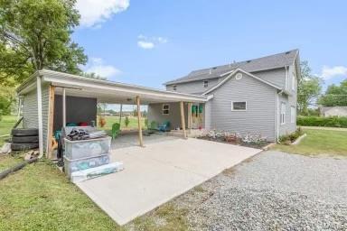 rear view of property featuring driveway, a carport, and a yard