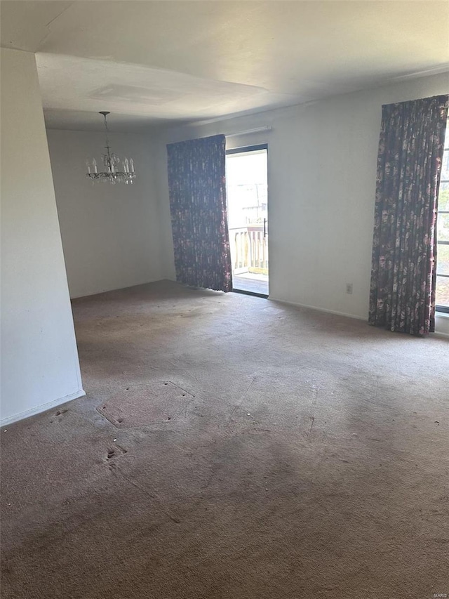 empty room with carpet and a notable chandelier