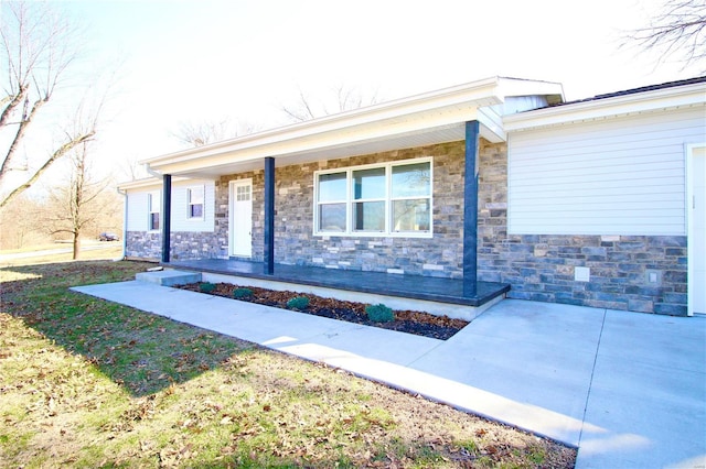 doorway to property with stone siding and a porch