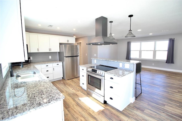 kitchen with island range hood, decorative backsplash, appliances with stainless steel finishes, a center island, and light wood-type flooring