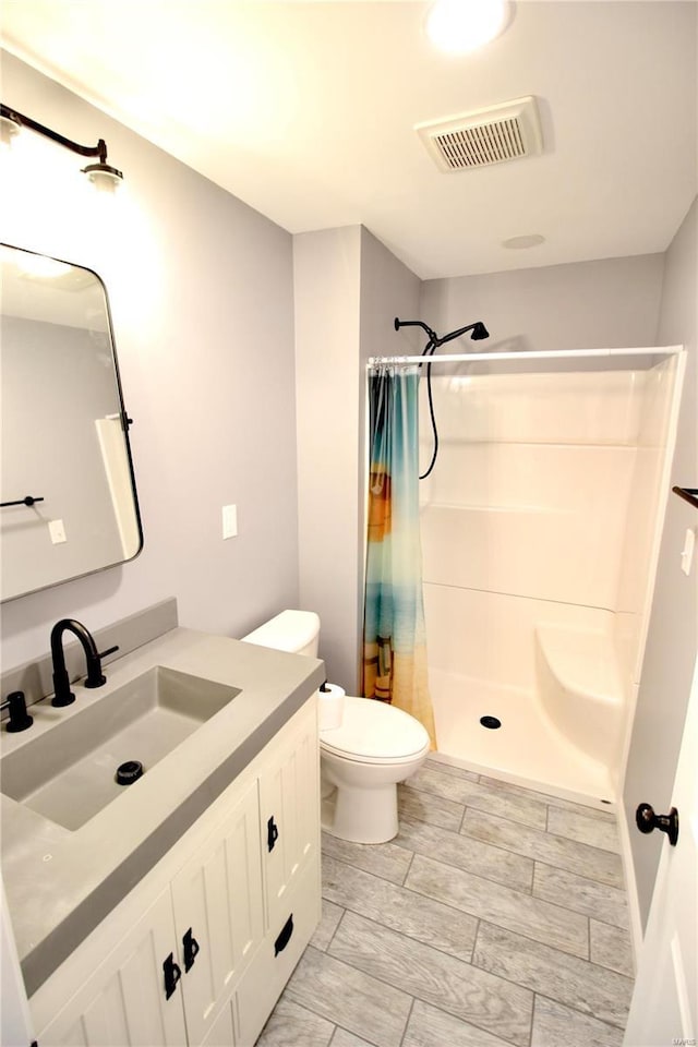 full bath featuring toilet, a stall shower, vanity, and visible vents