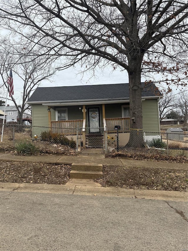 view of front of property featuring roof with shingles, a porch, a fenced front yard, and a gate