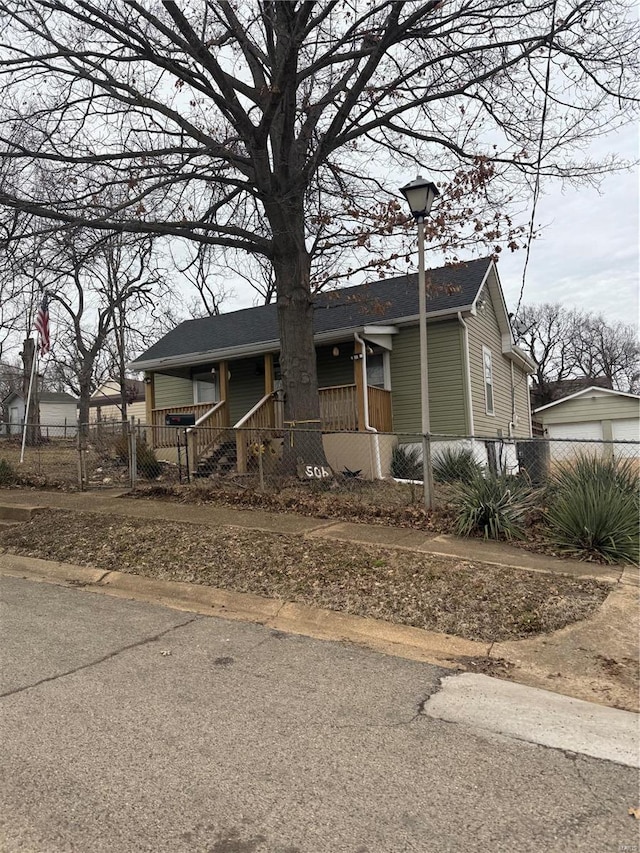 view of front of house featuring a fenced front yard, a porch, and roof with shingles