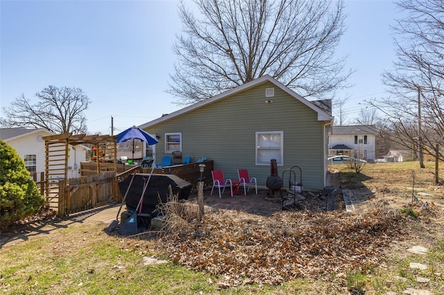 rear view of house featuring a pergola and fence