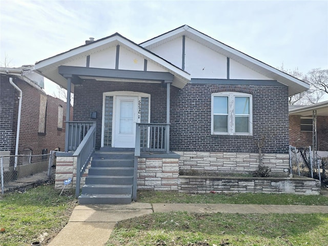 bungalow with brick siding, a porch, and fence