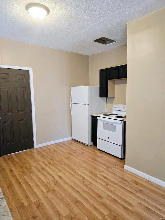 kitchen with baseboards, white appliances, light wood-style floors, and a textured ceiling