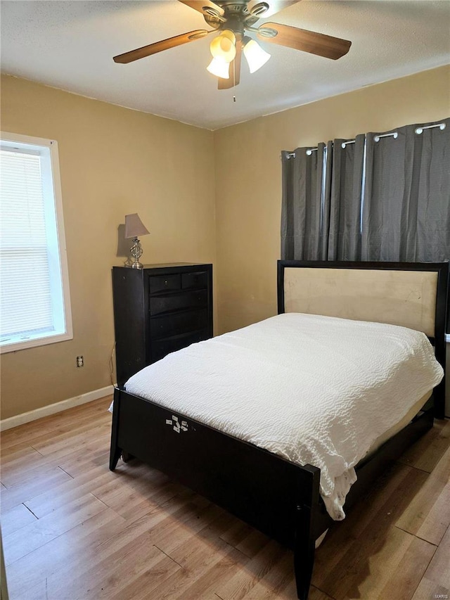 bedroom with light wood-type flooring, baseboards, and a ceiling fan