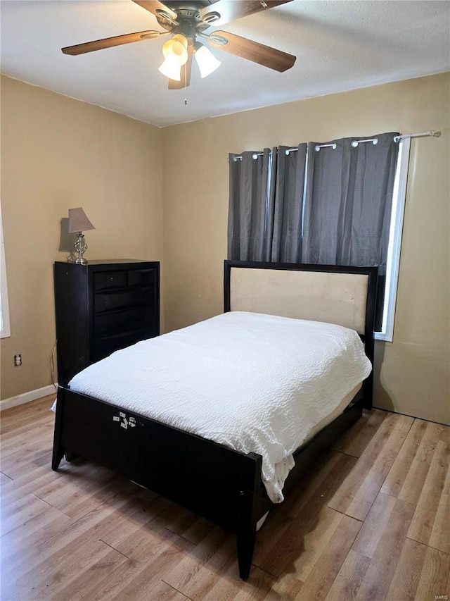 bedroom with baseboards, light wood-style flooring, and a ceiling fan