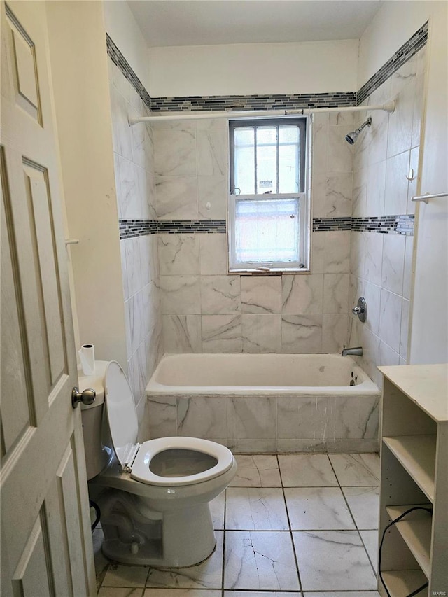 full bath with tiled shower / bath combo, toilet, marble finish floor, and vanity