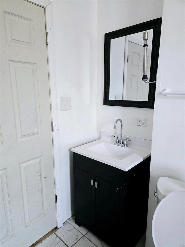 half bath featuring vanity, toilet, and marble finish floor