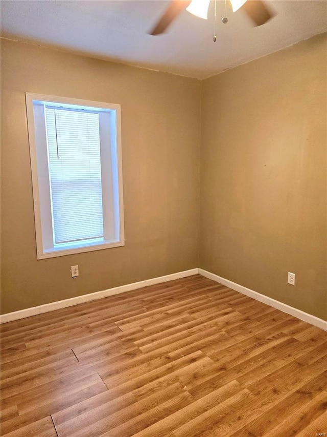 empty room featuring a ceiling fan, baseboards, and wood finished floors