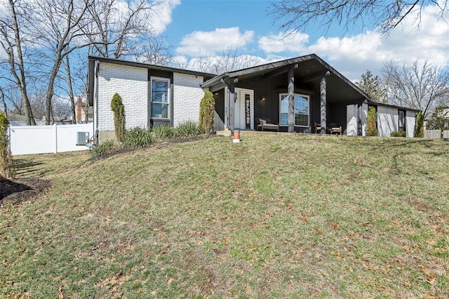 mid-century inspired home featuring a front yard, brick siding, and fence