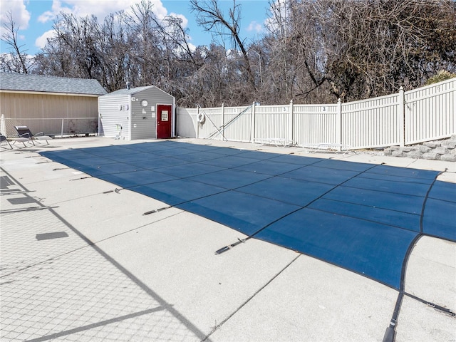 view of swimming pool with an outbuilding, a patio, fence, a fenced in pool, and a storage unit