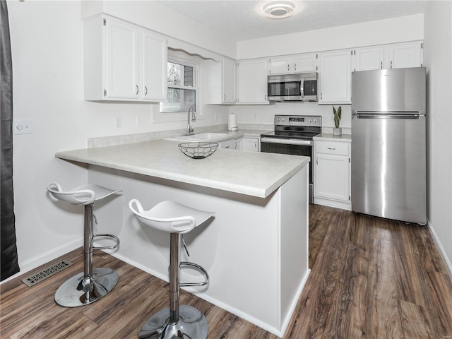 kitchen featuring white cabinets, stainless steel appliances, light countertops, and a sink