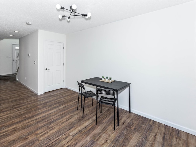 dining area featuring a notable chandelier, baseboards, a textured ceiling, and dark wood finished floors