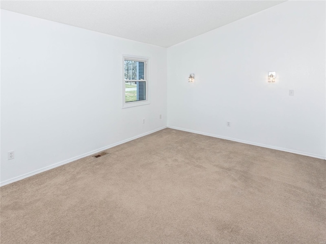 spare room with visible vents, light colored carpet, and baseboards