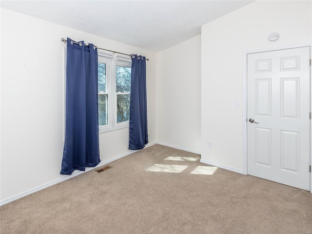 carpeted spare room featuring visible vents, a textured ceiling, and baseboards