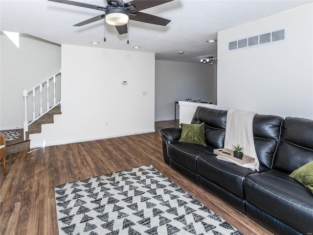 living area featuring visible vents, baseboards, stairway, wood finished floors, and a textured ceiling