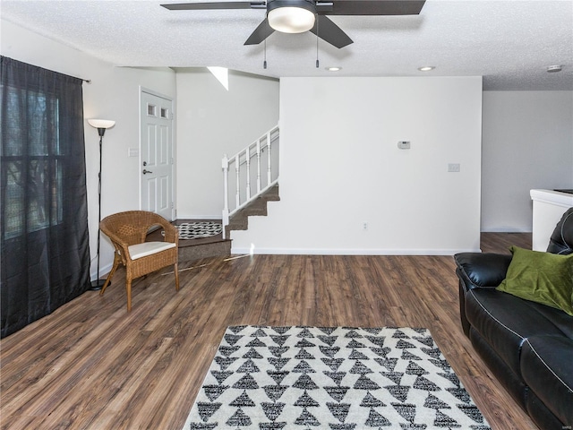 living room with stairway, wood finished floors, baseboards, and a textured ceiling