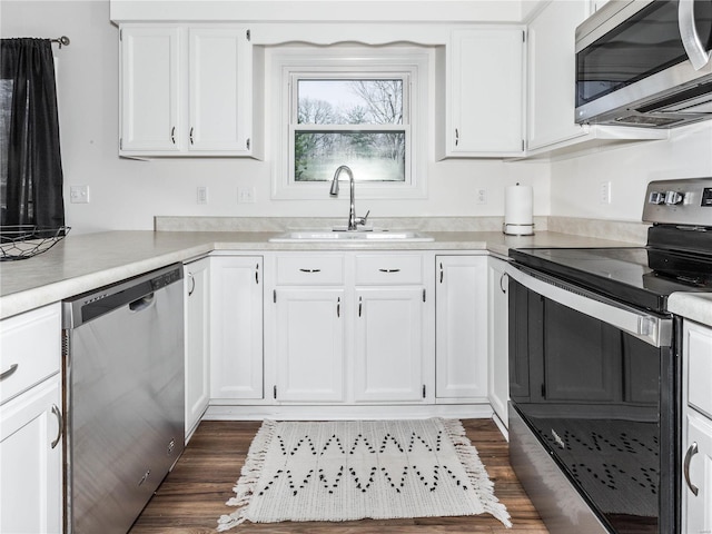 kitchen featuring a sink, white cabinetry, appliances with stainless steel finishes, light countertops, and dark wood-style flooring