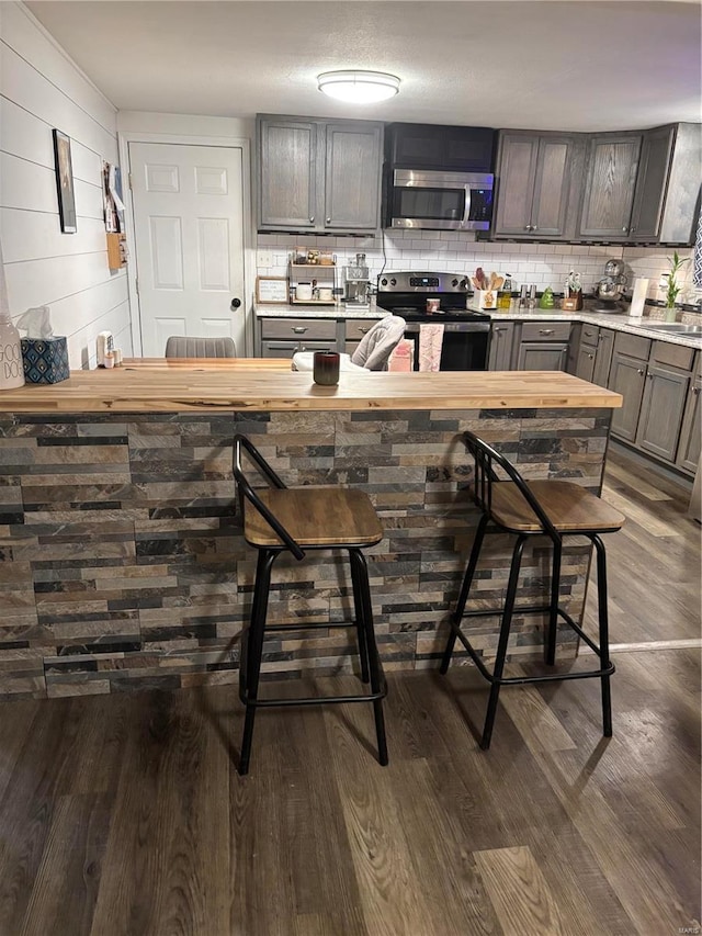 kitchen featuring light countertops, backsplash, wood finished floors, and appliances with stainless steel finishes