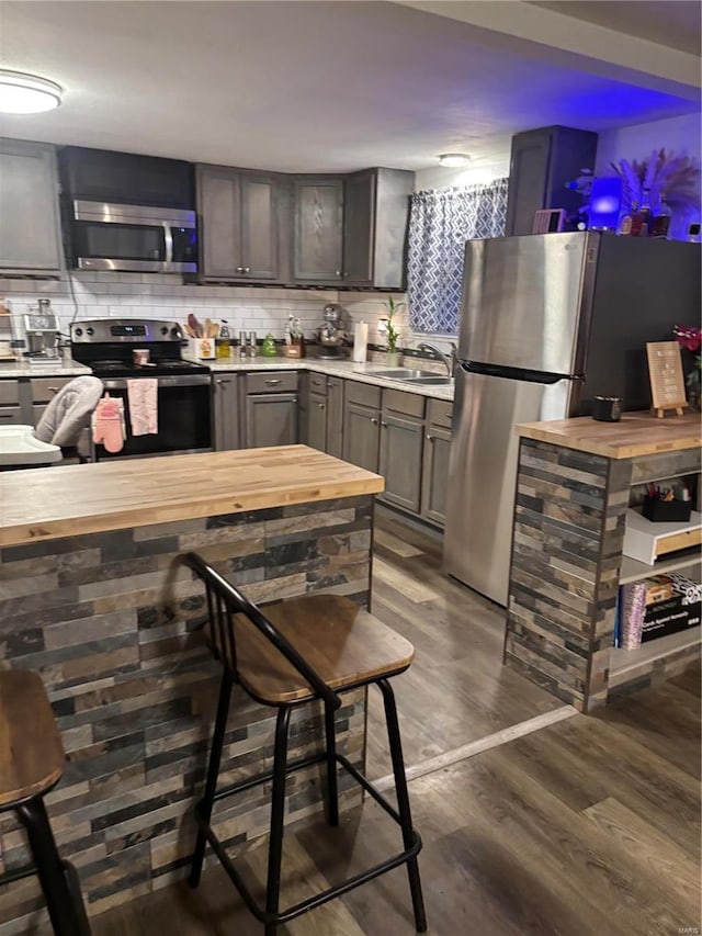 kitchen with stainless steel appliances, wooden counters, backsplash, and dark wood finished floors