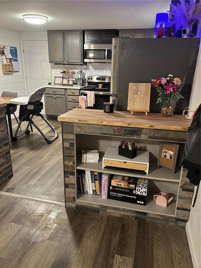 kitchen with open shelves, wood counters, tasteful backsplash, wood finished floors, and appliances with stainless steel finishes