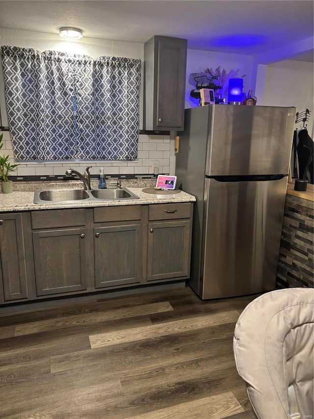 kitchen featuring a sink, freestanding refrigerator, decorative backsplash, dark brown cabinets, and dark wood-style flooring