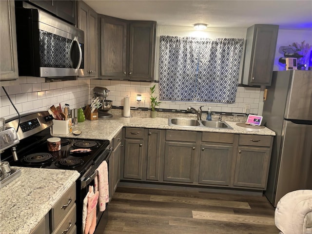 kitchen featuring a sink, decorative backsplash, dark wood-type flooring, and appliances with stainless steel finishes