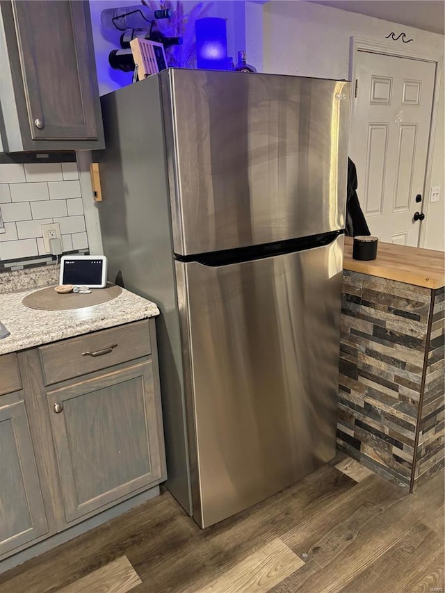 kitchen with decorative backsplash, dark wood finished floors, and freestanding refrigerator