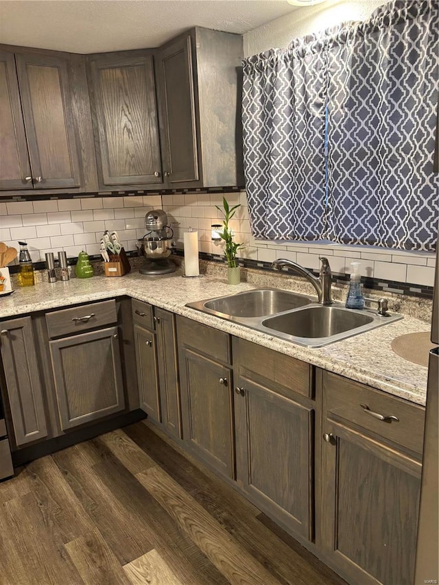 kitchen with a sink, backsplash, and dark wood-style flooring