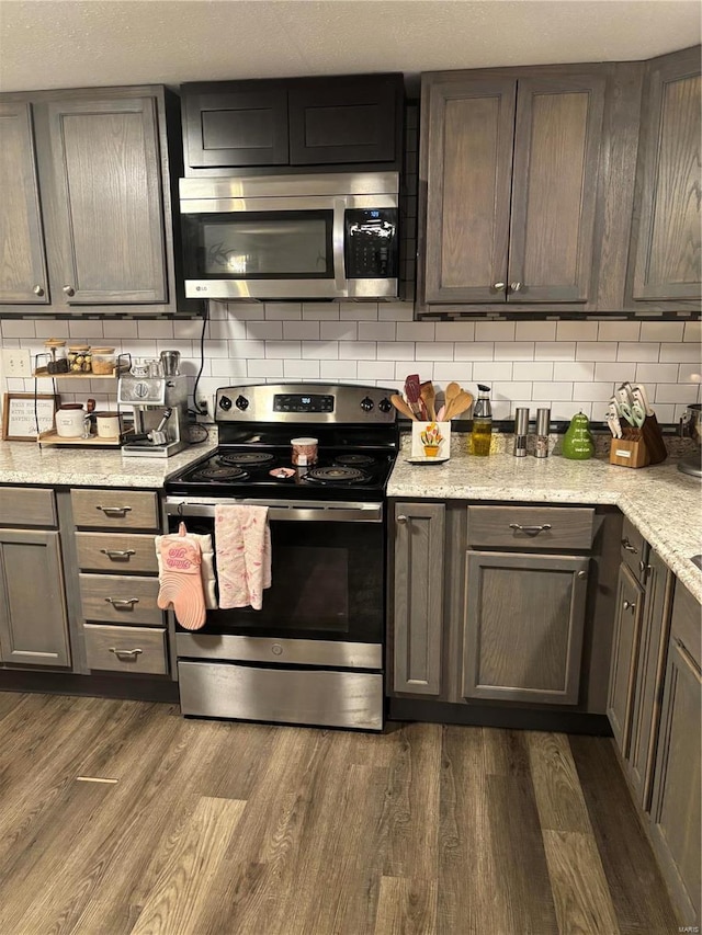 kitchen with backsplash, appliances with stainless steel finishes, and dark wood-style floors