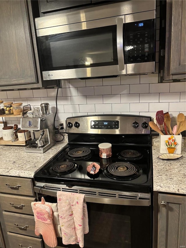 kitchen featuring decorative backsplash, dark brown cabinetry, light stone countertops, and stainless steel appliances