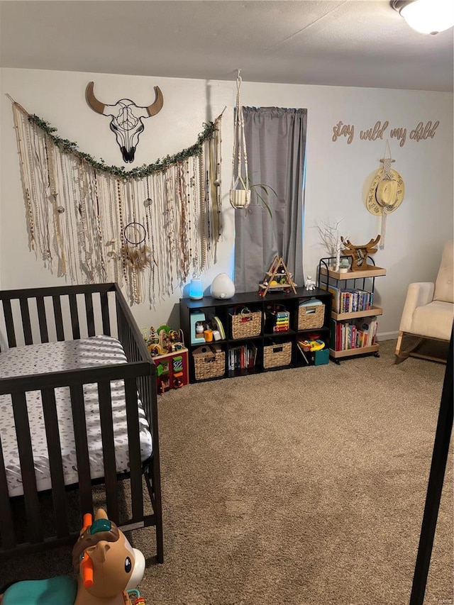 bedroom featuring a nursery area and carpet floors