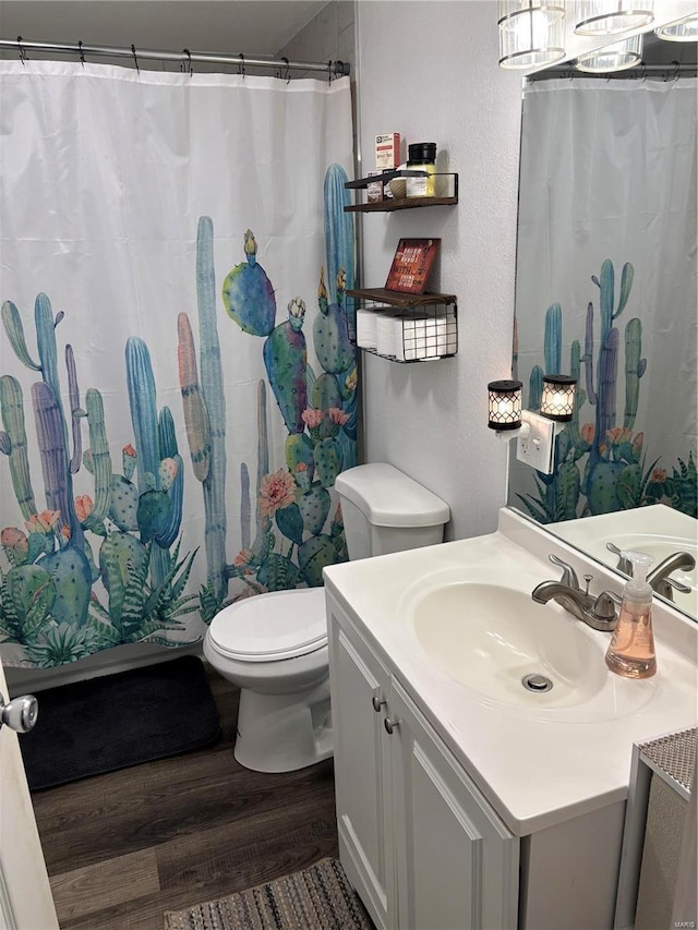 full bath featuring toilet, curtained shower, wood finished floors, vanity, and a textured wall