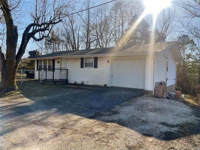 view of front of property featuring aphalt driveway, an attached garage, and a gate